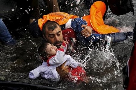 Một người nhập cư Syria đang ôm đứa con khi cố bơi vào bờ ở đảo Lesbos, Hy Lạp, sau khi vượt biển. Ảnh: Reuters