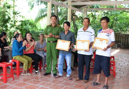 Trung tá Trần Văn Tiếng- Trưởng Công an Phường 8 trao giấy khen và tiền thưởng cho ba người dân.