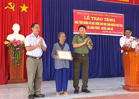 Phó Giám đốc Công an tỉnh- Nguyễn Thanh Bình trao tiền xây nhà tình nghĩa và học bổng cho các em học sinh.