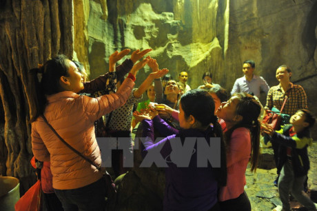 Các du khách đón những giọt nước từ nhũ đá trong động Hương Tích để cầu mong một năm mới nhiều sức khỏe, an lành và hạnh phúc. (Ảnh: Minh Đức/TTXVN)