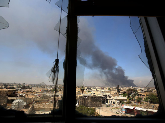 Một đám cháy nhìn từ cửa sổ bị vỡ của một tòa nhà ở Mosul.