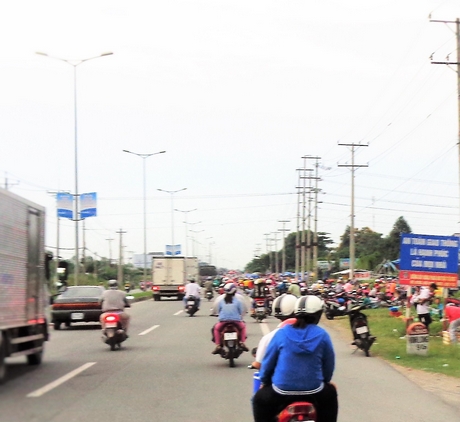 Trên QL1A đoạn trước cổng Khu công nghiệp Hòa Phú, phía sau bảng tuyên truyền với khẩu ngữ “An toàn giao thông là hạnh phúc của mọi nhà” là cảnh bán mua làm mất an toàn giao thông.