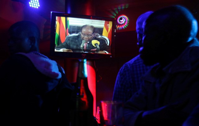 Người dân Zimbabwe xem tổng thống phát biểu trên đài truyền hình quốc gia tại một quán bar ở Harare - Ảnh: REUTERS