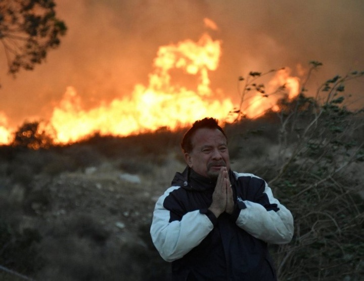 Một người đàn ông cầu nguyện trong khi đám cháy Creek đang thiêu rụi vùng Sylmar, California - Ảnh: REUTERS