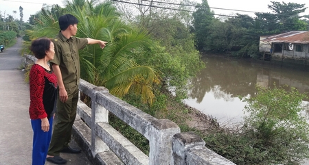Đồng chí Nguyễn Hoàng Vũ và bà Nguyễn Thị Lộc chỉ đoạn sông 2 em học sinh đuối nước.