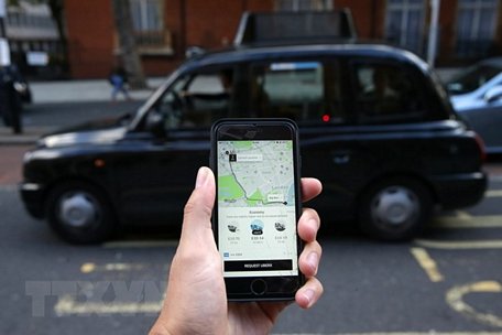 Một khách hàng dùng điện thoại di động để gọi dịch vụ xe của Uber. (Nguồn: AFP/TTXVN)