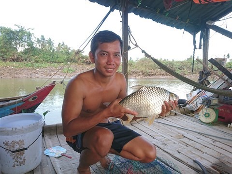 Ngư dân Hồng Sơn và con cá mè Vinh mới câu được trên sông Vàm Nao.