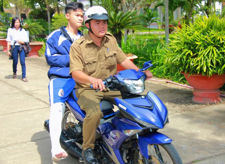 Thí sinh bị tai nạn được lực lượng hỗ trợ chở từ phòng thi ra cổng trường (tại điểm thi THPT Phan Văn Hòa).