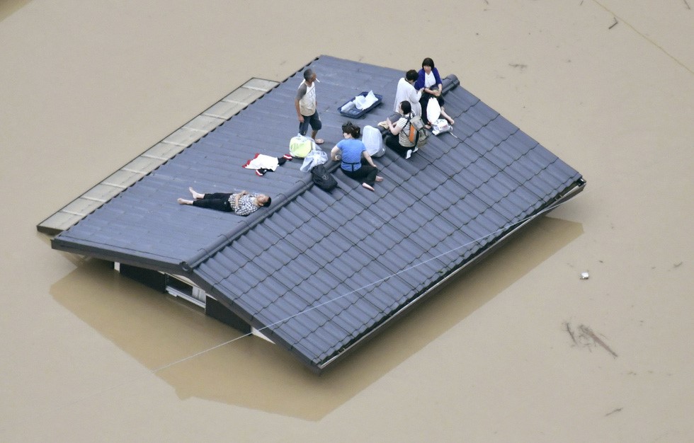 Người dân phải trèo lên mái nhà do nước lụt và chờ lực lượng giải cứu tại TP Kurashiki, phía nam Nhật, ngày 7/7 - Ảnh: REUTERS