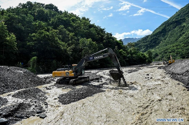 Một máy xúc cặm cụi dọn bùn đá dưới lòng một con sông ở Khương Bắc Xuyên, Tứ Xuyên, Trung Quốc. Giới chức địa phương cho biết một số người vẫn đang mắc kẹt trong các khu vực bị lũ lụt chia cách. Các nhân viên cứu hộ đang làm việc cả ngày lẫn đêm để tiếp cận những người này.
