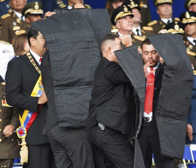 Ngay lập tức, các nhân viên an ninh đã chạy đến vây quanh và dùng những tấm khiên đen chống đạn để bảo vệ ông Maduro. Ảnh: AP.