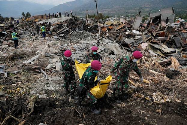  Những người lính Indonesia đang khiêng một thi thể ra khỏi đống đổ nát ở quận Balaroa sau thảm họa động đất sóng thần kinh hoàng ngày 28/9. Ảnh: Reuters