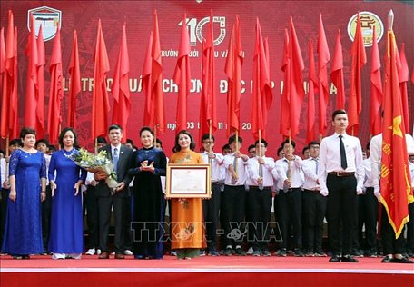 Chủ tịch Quốc hội Nguyễn Thị Kim Ngân gắn Huân chương Độc lập hạng Ba lên lá cờ truyền thống của trường. Ảnh: Trọng Đức/TTXVN