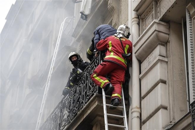 Lực lượng cứu hỏa hỗ trợ người mắc kẹt trong tòa nhà sau vụ nổ ở trung tâm Paris, Pháp ngày 12/1/2019. (Ảnh: AFP/TTXVN)