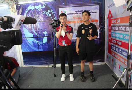 Một học sinh (phải) tham gia làm MC dưới sự hướng dẫn của sinh viên Trường cao đẳng Phát thanh truyền hình II - Ảnh: CHÍ QUỐC
