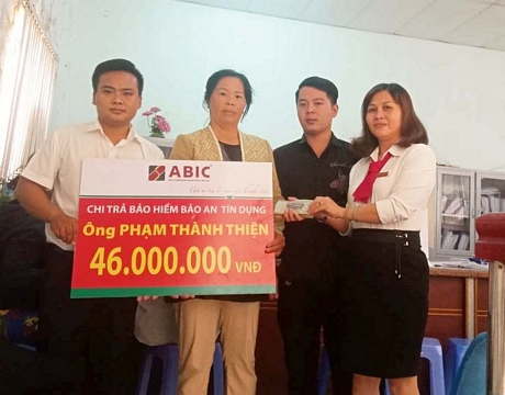 Đại diện ABIC (bên trái) và đại diện Agribank huyện Bình Tân (bên phải) trao biểu trưng chi trả bảo hiểm cho gia đình khách hàng.