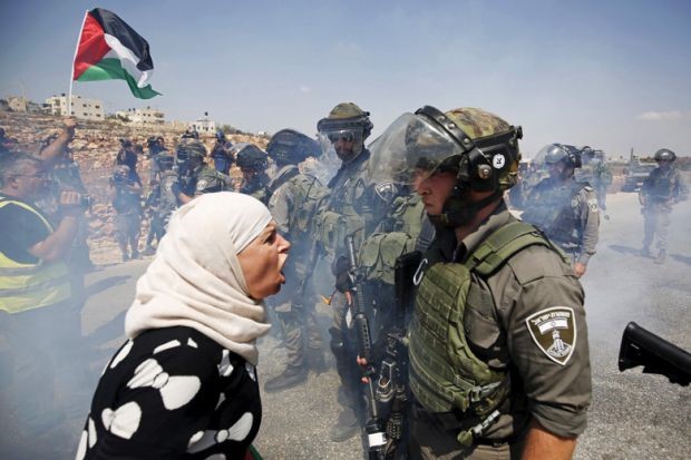 Một phụ nữ Palestine va chạm với lính Israel. Ảnh: Getty