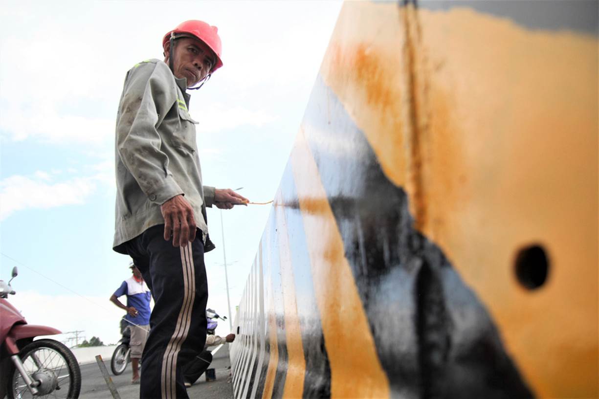 Một công nhân đang sơn lại dải phân cách trên cầu để chuẩn bị cho ngày thông xe - Ảnh: MẬU TRƯỜNG