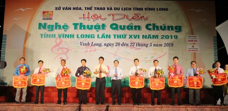 Phó Chủ tịch UBND tỉnh- Lữ Quang Ngời (thứ 5 từ trái sang) và Phó Giám đốc Sở Văn hóa, Thể thao và Du lịch- Lê Thanh Hiền  trao cờ lưu niệm cho các đơn vị tham gia hội diễn.