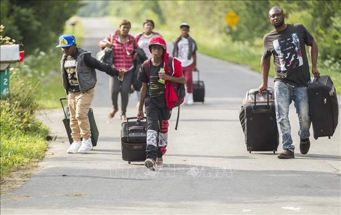 Người di cư từ Haiti di chuyển tại Champlain, New York (Mỹ) để chuẩn bị băng qua biên giới sang Canada ngày 4/8/2017. Ảnh: AFP/TTXVN