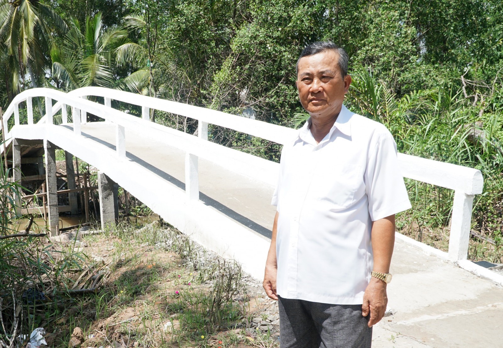 Ông Lâm Văn Phấn bên chiếc cầu bê-tông do ông vận động xây dựng.