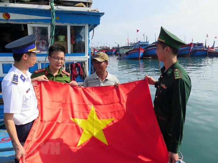Cán bộ Vùng Cảnh sát biển 2 tặng cờ Tổ quốc cho ngư dân huyện đảo Lý Sơn, tỉnh Quảng Ngãi. (Ảnh: Đỗ Trưởng/TTXVN)