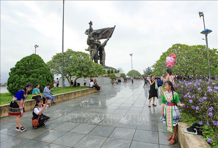 Các thiếu nữ Mông chụp ảnh lưu niệm trên Tượng đài Chiến thắng Điện Biên Phủ. Ảnh: Xuân Tư/TTXVN