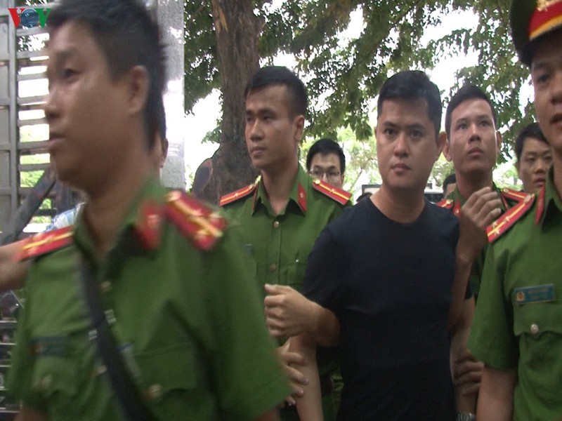 Lực lượng công an áp giải bác sĩ Lê Quang Huy Phương (áo đen).