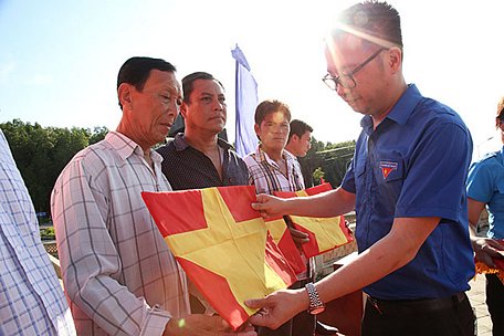  Phó Chủ tịch Thường trực T.Ư Hội LHTN Việt Nam Nguyễn Tường Lâm trao quốc kỳ tặng ngư dân địa phương vươn khơi bám biển.