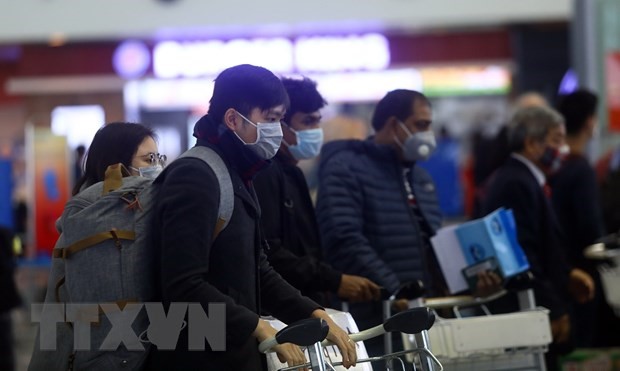 Hành khách trang bị khẩu trang kín mít khi đến sân bay quốc tế Nội Bài. (Ảnh: Huy Hùng/TTXVN)