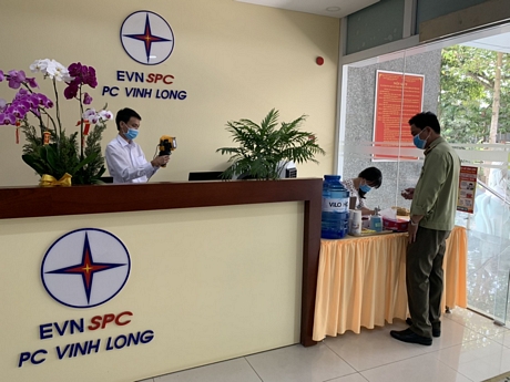 Khách hàng đến Văn phòng Công ty Điện lực Vĩnh Long liên hệ công tác được phát khẩu trang để đeo và tờ rơi hướng dẫn phòng bệnh.