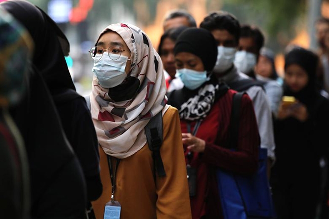 Người dân Kuala Lumpur (Malaysia) đeo khẩu trang ngừa dịch viêm phổi do virus Corona mới tại một trạm dừng xe buýt.