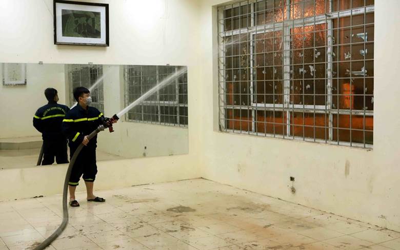  Lính cứu hỏa phun nước vệ sinh các phòng dùng để làm bệnh viện dã chiến. (Ảnh: Hoàng Hùng/TTXVN)
