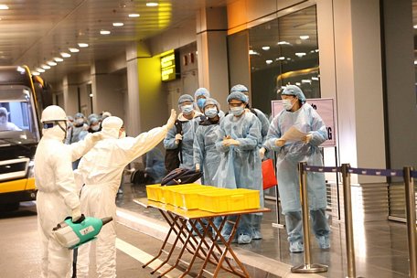 Công dân Việt Nam được khử trùng trước khi làm thủ tục nhập cảnh tại sân bay Vân Đồn (Quảng Ninh). (Ảnh: Dương Giang/TTXVN)