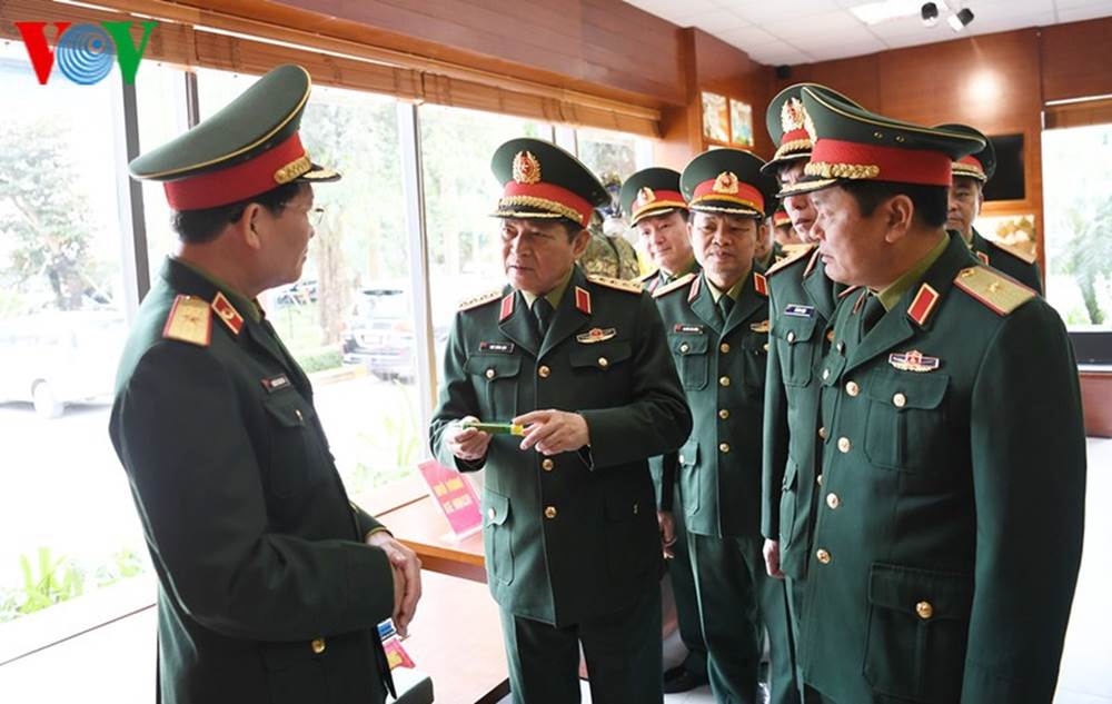 Cục trưởng Cục Quân y Nguyễn Đức Kiên (ngoài cùng bên trái) giới thiệu với Bộ trưởng Ngô Xuân Lịch mô hình xi lanh tự tiêm, dành cho người bệnh đang được Cục Quân y hoàn thiện và sắp đưa vào sử dụng.