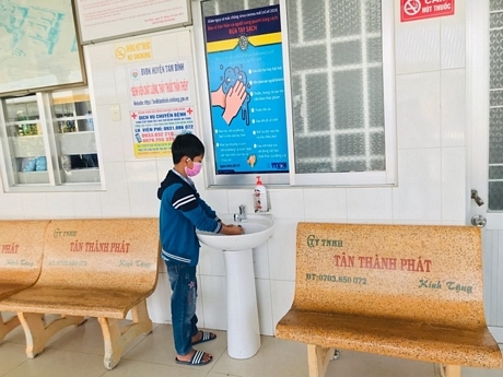 Trẻ em đến khám tại Trung tâm Y tế huyện Tam Bình được hướng dẫn rửa tay trước khi vào phòng khám.