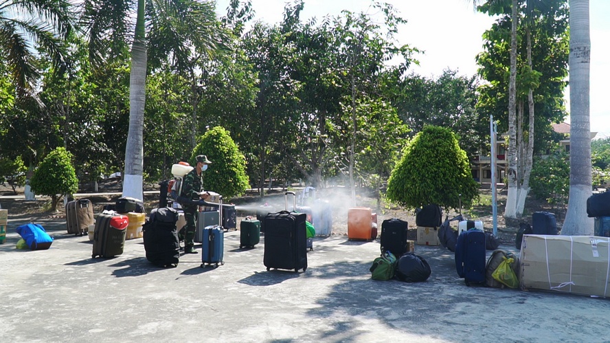 Bộ đội giúp những người sau cách ly đưa hành lý ra xe và thực hiện khử trùng hành lý trước khi ra về.