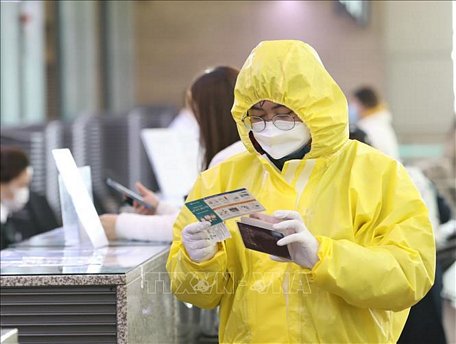 Một hành khách đeo khẩu trang và mặc quần áo bảo hộ phòng lây nhiễm COVID-19 tại sân bay quốc tế Incheon ở Incheon, Hàn Quốc, ngày 13/3. Ảnh: THX/TTXVN