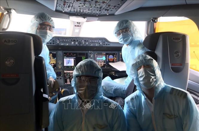  Các phi công, tiếp viên mặc trang phục bảo hộ trước khi thực hiện chuyến bay, cùng găng tay, khẩu trang, kính mắt, khăn tẩm cồn và dung dịch sát khuẩn. Ảnh: TTXVN phát