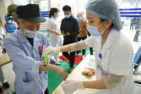 Bệnh nhân được đo tha6n nhiệt và sát khuẩn tay trước khi vào khám bệnh tại Bệnh viện K Hà Nội - Ảnh: BỆNH VIỆN CUNG CẤP