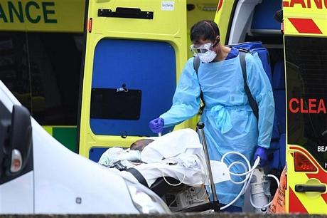 Nhân viên y tế chuyển bệnh nhân mắc COVID-19 từ xe cứu thương vào bệnh viện St Thomas ở London, Anh ngày 31/3/2020. Ảnh: AFP/TTXVN