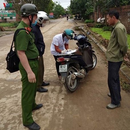 Lực lượng công an huyện lập biên bản xử phạt người dân không đeo khẩu trang khi ra ngoài đường.