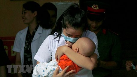Bác sỹ Bùi Thị Liệu, cán bộ Trung tâm xét nghiệm CDC tỉnh Hòa Bình xúc động chia tay bé Trường An (Hà Tĩnh) 5 tháng tuổi trong ngày hoàn thành cách ly. (Ảnh: Trọng Đạt/TTXVN)