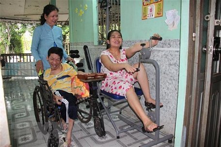 Bà Trần Thị Như Yến (xã Trà Côn, huyện Trà Ôn) và hai con bị nhiễm chất độc da cam luyện tập phục hồi chức năng. (Ảnh: Lê Thúy Hằng/TTXVN)