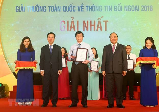  Thủ tướng Nguyễn Xuân Phúc và Trưởng ban Tuyên giáo Trung ương trao giải nhất Giải thưởng toàn quốc thông tin đối ngoại năm 2018 cho tác giả Lê Trí Dũng (TTXVN). (Ảnh: Doãn Tấn/TTXVN)