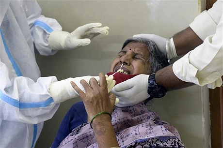 Nhân viên y tế lấy mẫu dịch xét nghiệm COVID-19 cho người dân tại Hyderabad, Ấn Độ. Ảnh: AFP/ TTXVN