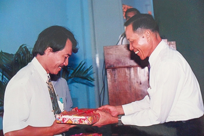 Ông Lê Côn Tòng (bên phải) tặng quà lưu niệm cho ông Lê Quốc Phong- Giám đốc Nhà máy Phân bón Bình Điền II.