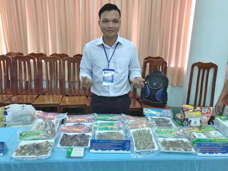 Phan Chao tại gian hàng trưng bày và bàn sản phẩm khô cá đồng.