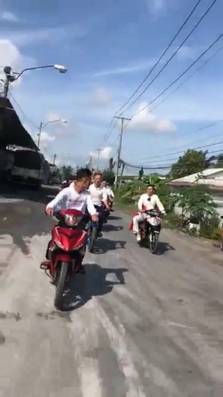 Nhóm thanh niên tham gia rước dâu bằng xe gắn máy nhưng không đội mũ bảo hiểm, điều khiển xe thành đoàn gây cản trở giao thông. Ảnh cắt từ clip.
