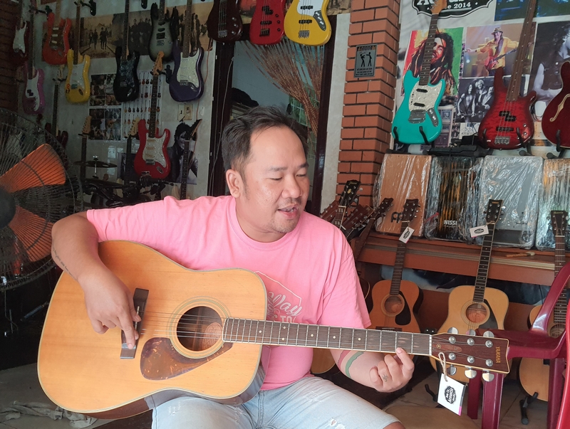 Nguyễn Duy đang cân chỉnh lại cây guitar.